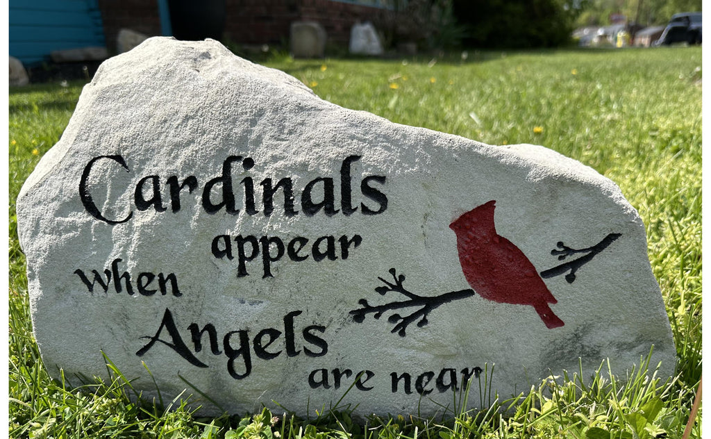A large, grey landscape stone with an irregular, rounded shape. The left hand side of the stone is slightly taller than the right size of the stone. The stone sits upright giving a nice face to engrave upon. The stone has a rustic, handcrafted appearance with natural texture and subtle color variations. This stone has the text Cardinals appear when angels are near along with a cardinal on a tree branch. The text & branch are painted black, the cardinal is a bold red color.