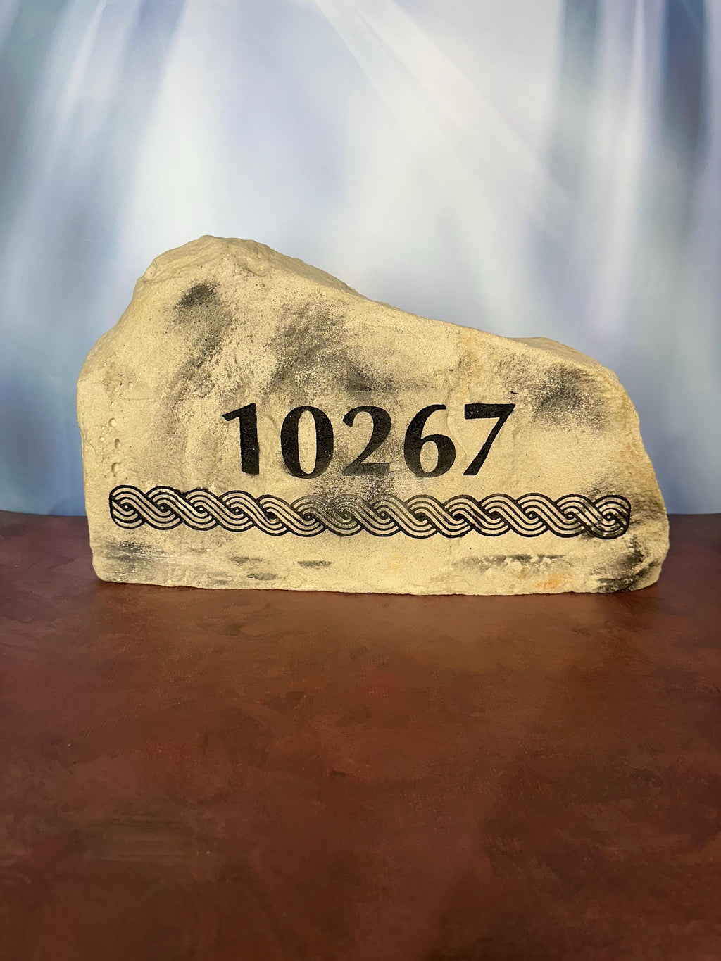 A large, grey landscape stone with an irregular, rounded shape. The left hand side of the stone is slightly taller than the right size of the stone. The stone sits upright giving a nice face to engrave upon. The stone has a rustic, handcrafted appearance with natural texture and subtle color variations. This stone has an address and a custom design underneath it.